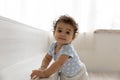 Adorable little african baby relying on furniture, making first steps. Royalty Free Stock Photo