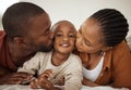 Portrait of adorable little african american boy lying between his mother and father on a bed at home home. Loving Royalty Free Stock Photo