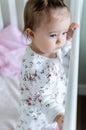 Portrait of adorable little baby girl staying at her bed in full-length