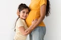 Portrait of adorable little girl embracing pregnant mother& x27;s belly, closeup shot Royalty Free Stock Photo