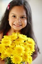 Portrait of adorable little girl holding bouquet of chrysanthemums at home. One cute child standing alone with bunch of