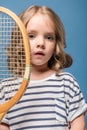 portrait of adorable little girl holding tennis raquet and looking at camera