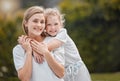 Portrait of an adorable little girl hugging her mother from behind while bonding with her in the garden at home Royalty Free Stock Photo