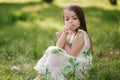 Portrait of adorable little girl sits barefoot on the grass in the park. Happy kid on the fresh air Royalty Free Stock Photo