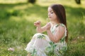 Portrait of adorable little girl sits barefoot on the grass in the park. Happy kid on the fresh air Royalty Free Stock Photo