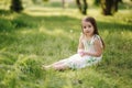 Portrait of adorable little girl sits barefoot on the grass in the park. Happy kid on the fresh air Royalty Free Stock Photo