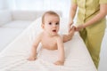 Portrait of adorable little infant boy getting massage from female masseuse massaging newborn baby feet with thumbs