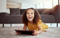 Portrait of adorable little mixed race child using digital tablet in home living room. One small cute hispanic girl Royalty Free Stock Photo