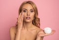 Portrait of adorable model having white jar with effective cream, applying under eyes, botox effect, fighting with dark circles,