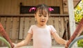 Portrait of adorable and pretty asian girl in pink ballet dress playing alone in playground for swing and climbing shows happiness Royalty Free Stock Photo