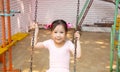 Portrait of adorable and pretty asian girl in pink ballet dress playing alone in playground for swing and climbing shows happiness Royalty Free Stock Photo