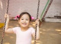 Portrait of adorable and pretty asian girl in pink ballet dress playing alone in playground for swing and climbing shows happiness Royalty Free Stock Photo