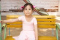 Portrait of adorable and pretty asian girl in pink ballet dress sitting lonely on swing in playground alone shows sadness of kid Royalty Free Stock Photo