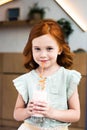 portrait of adorable redhead girl drinking milkshake from glass and smiling