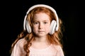 Portrait of adorable redhead girl listening music with headphones looking at camera Royalty Free Stock Photo