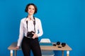 Portrait of adorable satisfied lady stand near desktop smile look camera isolated on blue color background