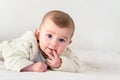 Portrait of an adorable smiling baby biting her own fingers putting her fist in her mouth Royalty Free Stock Photo