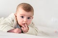 Portrait of an adorable smiling baby biting her own fingers putting her fist in her mouth Royalty Free Stock Photo