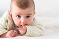 Portrait of an adorable smiling baby biting her own fingers putting her fist in her mouth Royalty Free Stock Photo