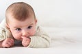 Portrait of an adorable smiling baby biting her own fingers putting her fist in her mouth Royalty Free Stock Photo