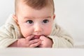 Portrait of an adorable smiling baby biting her own fingers putting her fist in her mouth Royalty Free Stock Photo