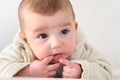 Portrait of an adorable smiling baby biting her own fingers putting her fist in her mouth Royalty Free Stock Photo