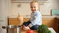 Portrait of adorable smiling baby boy sitting on kitchen table full of fruits and vegetables Royalty Free Stock Photo
