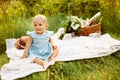 Portrait of adorable smiling baby girl sitting on blanket at the park with basket and flowers, parents with beautiful Royalty Free Stock Photo