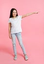 Portrait of adorable smiling little girl child preteen in the white t-shirt pointing to something by forefinger isolated Royalty Free Stock Photo