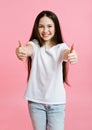 Portrait of adorable smiling little girl child in the white t-shirt with two fingers up isolated on a pink