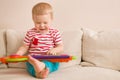 Portrait of adorable toddler boy sitting on the sofa and playing toy piano. Early learning at home. Little musician. Child and Royalty Free Stock Photo