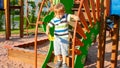 Portrait of adorable 3 years old boy climbing on ladder on the children palyground at park