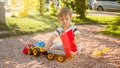 Portrait of adorable 3 years old toddler boy playing with toy truck with trailer on the playground at park. Child Royalty Free Stock Photo