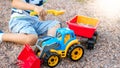 Portrait of adorable 3 years old toddler boy playing with toy truck with trailer on the playground at park. Child Royalty Free Stock Photo