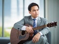 Portrait adult asian businessman very handsome and smart wearing suit relaxing by playing guitar feel casual and relaxation in Royalty Free Stock Photo