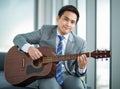 Portrait adult asian businessman very handsome and smart wearing suit relaxing by playing guitar feel casual and relaxation in