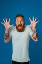 Portrait of adult bearded tattooed handsome man with raised hands