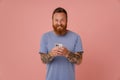 Portrait of adult bearded tattooed handsome smiling man with phone
