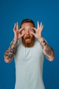 Portrait of adult bearded tattooed handsome stylish man holding eyes