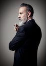 Portrait of adult businessman wearing trendy suit and holding cigarette against the empty wall. Vertical mockup