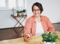 Portrait of adult charming brunette woman businesswoman in glasses plus size body positive using mobile at the home office