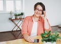 Portrait of adult charming brunette woman businesswoman in glasses plus size body positive using mobile at the home office
