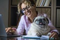 Portrait of adult cheerful young pretty woman and funny dog working together at laptop computer in home office room .- concept of Royalty Free Stock Photo