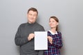 Portrait of adult couple holding together white blank paper sheet