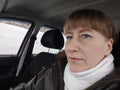 Portrait of adult cute funny blonde woman in warm clothes taking a selfie inside the car and driving it. The concept of