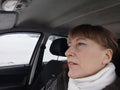 Portrait of adult cute funny blonde woman in warm clothes taking a selfie inside the car and driving it. The concept of