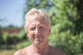 Portrait of an adult elderly European blonde man in a green garden on a summer day