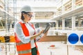 Portrait of adult female builder, engineer, architect, inspector, manager at construction site. Woman with plan, digital tablet Royalty Free Stock Photo