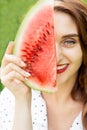 Portrait of adult girl holding slice of watermelon covering part of face Royalty Free Stock Photo