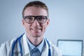 Portrait of adult handsome family doctor in medical office. Successful physician in white lab coat looking at camera and Royalty Free Stock Photo